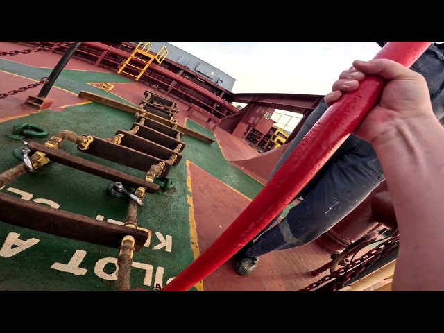 Climbing the rope ladder from a supplyboat to a bulk carrier. ship to ship bunkering in rough sea