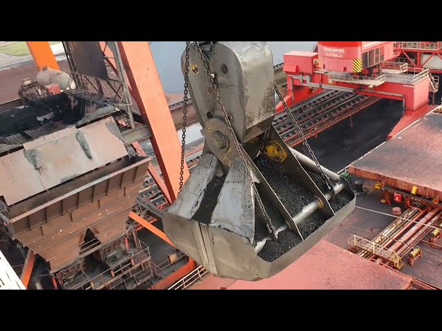 Unloading a 300 meter coal bulk ship. Bucket crane with massive bucket close to the wheelhouse