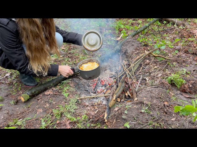 Girl cooking on campfire. Making a small tent alone in the wood. Cooking under the rain.
